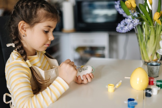 Szczęśliwa mała dziewczynka maluje pisanek na kuchni Śliczna uśmiechnięta dziewczyna bawić się na wakacjach wiosny