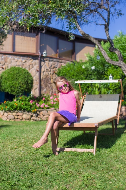Szczęśliwa mała dziewczynka na plażowym lounger outdoors