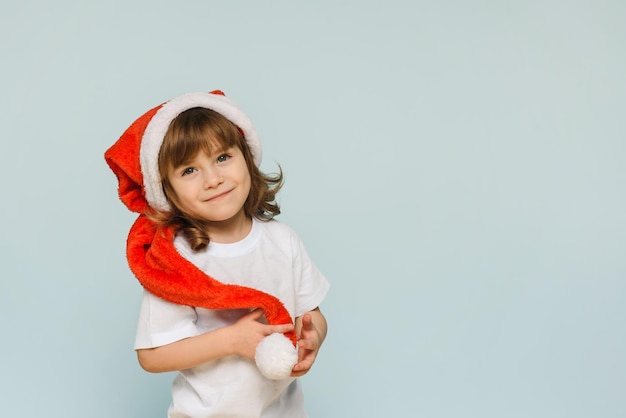 Szczęśliwa Mała Dziewczynka Uśmiecha Się W Santa Hat Na Niebieskim Tle Z Kopią Przestrzeni świątecznej Fotografii