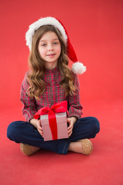 Szczęśliwa mała dziewczynka w Santa kapeluszowym mienie prezencie