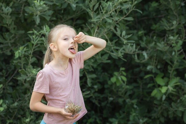 Szczęśliwa mała dziewczynka z filiżanką świeżych białych bobry na ciepły słoneczny dzień