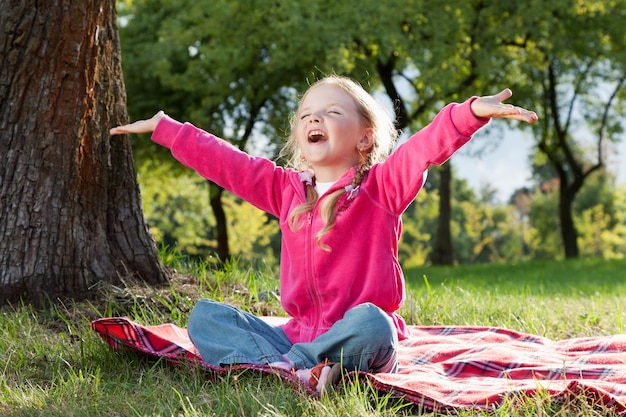 Szczęśliwa mała dziewczynka z rękami up w lato parku