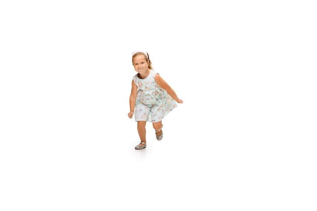 Szczęśliwa mała kaukaska dziewczynka skacząca i biegająca na białym tle
