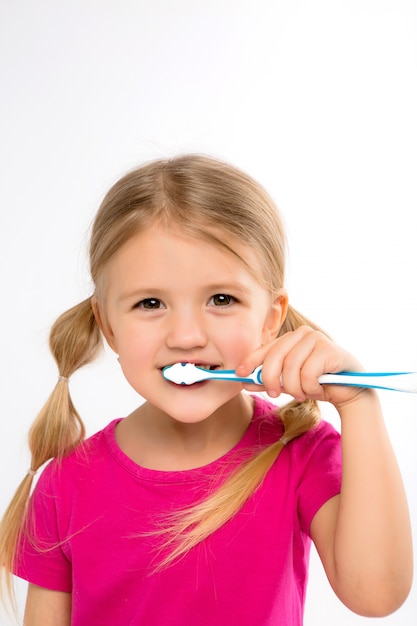 Szczęśliwa małej dziewczynki pozycja z toothbrush odizolowywającym na bielu.