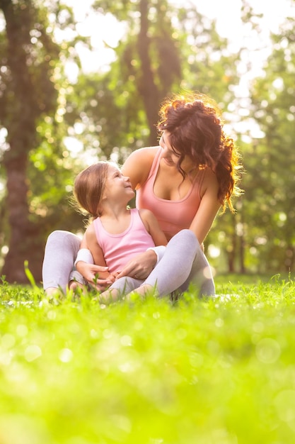 Szczęśliwa mama i córka siedzą razem w parku i patrzą na siebie