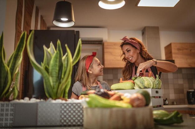 Szczęśliwa mama i jej córka cieszą się wspólnym przygotowywaniem i spożywaniem zdrowego posiłku w domowej kuchni.