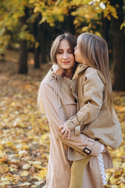 Szczęśliwa mama i jej piękna córka bawią się i spacerują po jesiennym parku.