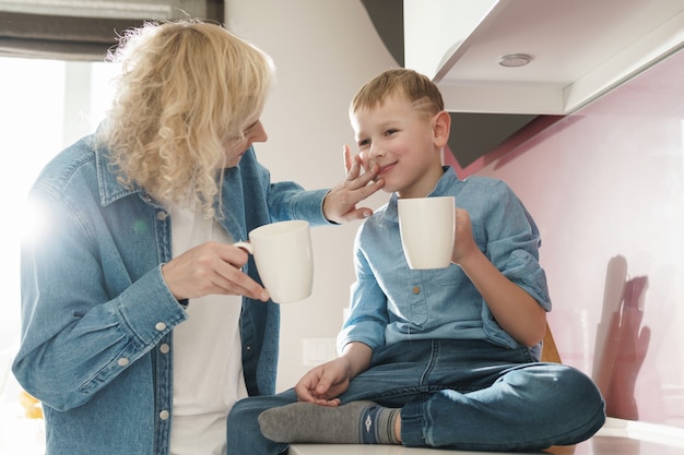 Szczęśliwa mama i jej uroczy syn piją herbatę w kuchni