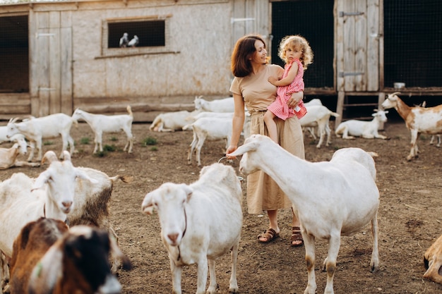 Szczęśliwa Mama Z Córką Spędzają Czas Na Ekologicznej Farmie Wśród Kóz.