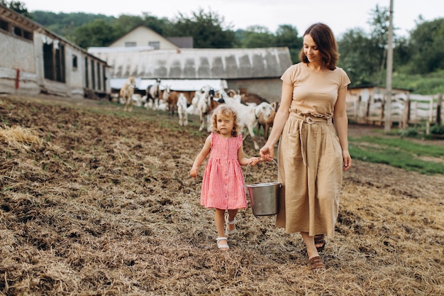 Szczęśliwa Mama Z Córką Spędzają Czas Na Ekologicznej Farmie Wśród Kóz.