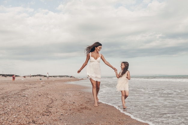 Zdjęcie szczęśliwa matka i córka cieszy się słonecznego dzień na plaży