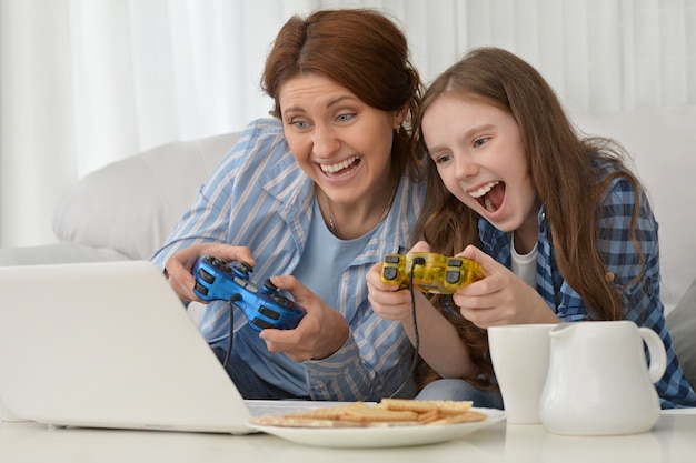 Szczęśliwa matka i córka grają w gry komputerowe na laptopie