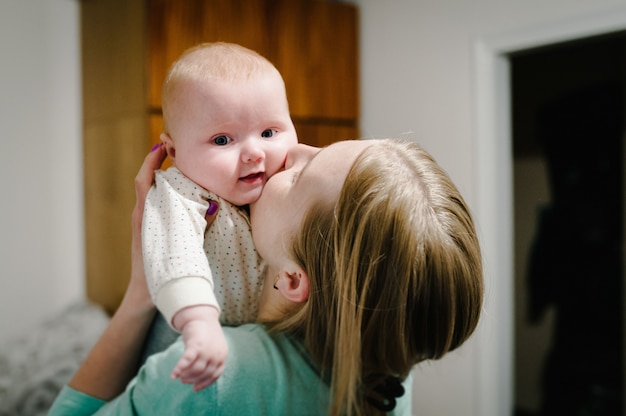 Szczęśliwa Matka I Córka. Mama Trzyma Się Za Ręce I Całuje Małą Córeczkę, Koncepcja Szczęśliwej Rodziny, Styl życia. Nowo Narodzony. Sesja Zdjęciowa 4-5 Miesięcy.