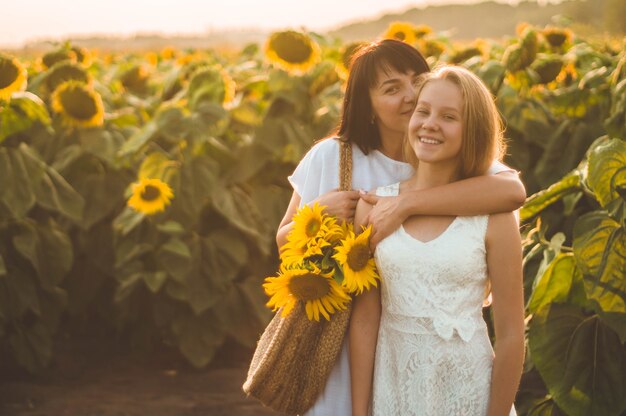 Szczęśliwa matka i jej córka nastolatek w słonecznikowym polu