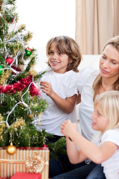 Szczęśliwa matka i jej dzieci wiesza Bożenarodzeniowe dekoracje