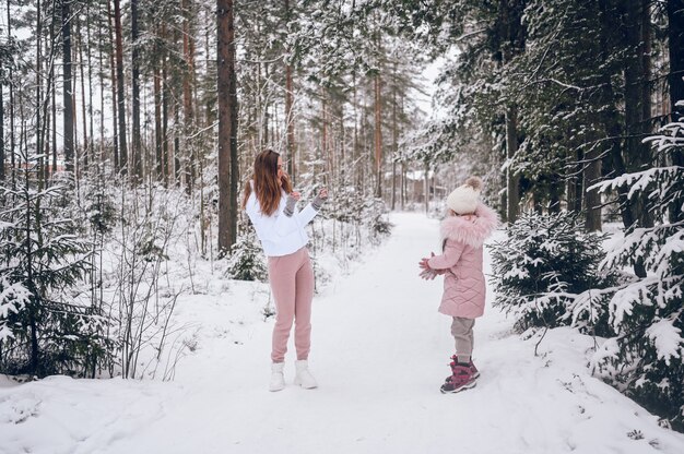 Szczęśliwa matka i mała śliczna dziewczyna w różowej ciepłej odzieży wierzchniej chodzenie grając na śnieżki zabawy w śnieżnobiałą zimę