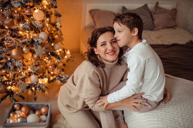 Szczęśliwa matka i syn w domu w sypialni w pobliżu choinki