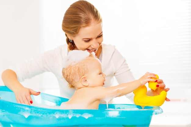Zdjęcie szczęśliwa matka rodziny kąpie dziecko w niebieskiej wannie