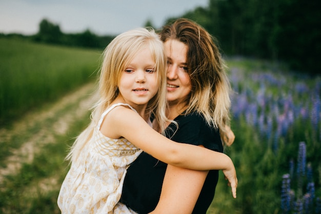 Szczęśliwa Matka ściska Jej Pięknej Uśmiechniętej Małej Blondynki Córki W Lata Polu.