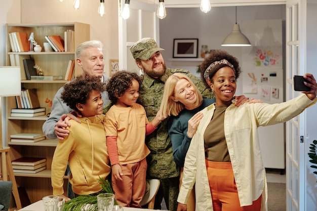 Szczęśliwa międzykulturowa sześcioosobowa rodzina robiąca selfie w salonie
