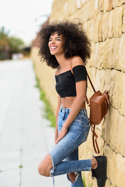 Szczęśliwa mieszana kobieta śmia się outdoors z afro włosy