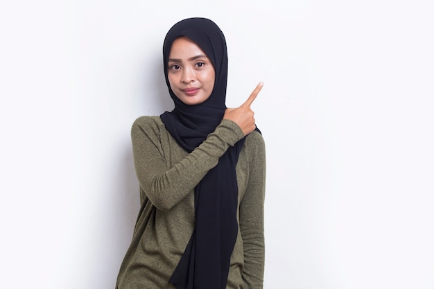 Szczęśliwa Młoda Azjatycka Muzułmańska Kobieta Wskazująca Palcami W Różnych Kierunkach Na Białym Tle