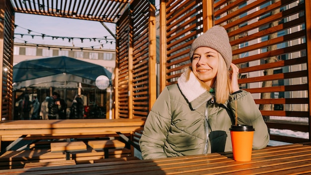 Szczęśliwa młoda blondynka w słoneczny zimowy dzień na ulicznych targach żywności