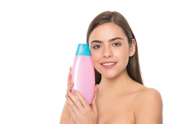 Szczęśliwa młoda dama trzyma butelkę balsamu do ciała na białym tle z szamponem kosmetycznym