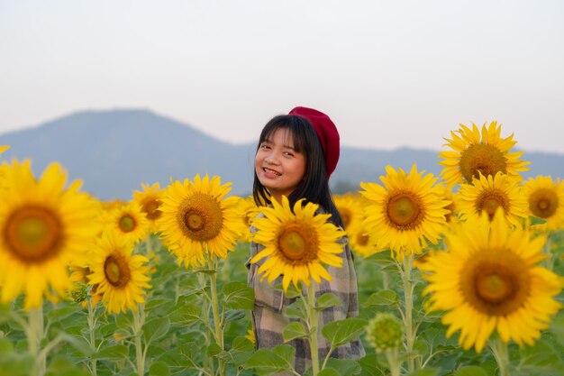 Szczęśliwa młoda dziewczyna na słonecznikowym polu z niebieskim niebem