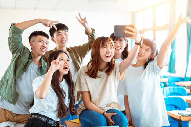 Szczęśliwa młoda grupa nastolatków robi zabawne selfie w klasie