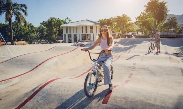 Szczęśliwa młoda kobieta cieszy się jazdą na BMX w skateparku