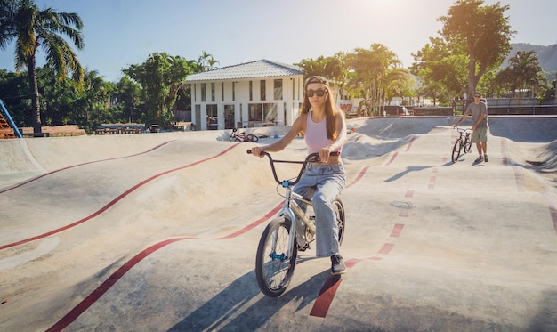 Zdjęcie szczęśliwa młoda kobieta cieszy się jazdą na bmx w skateparku