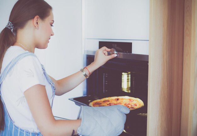 Szczęśliwa młoda kobieta gotuje pizzę w domu