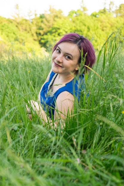 Szczęśliwa młoda kobieta leżąca w trawie w naturze latem