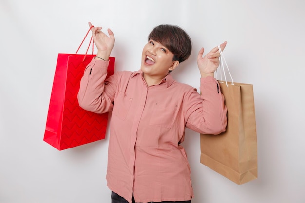 Szczęśliwa młoda kobieta ma na sobie różową koszulę i trzyma prezenty lub torbę na zakupy