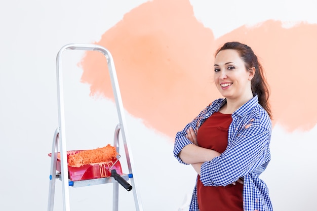Szczęśliwa młoda kobieta malowanie ścian w swoim nowym mieszkaniu. Koncepcja remontu, remontu i naprawy.