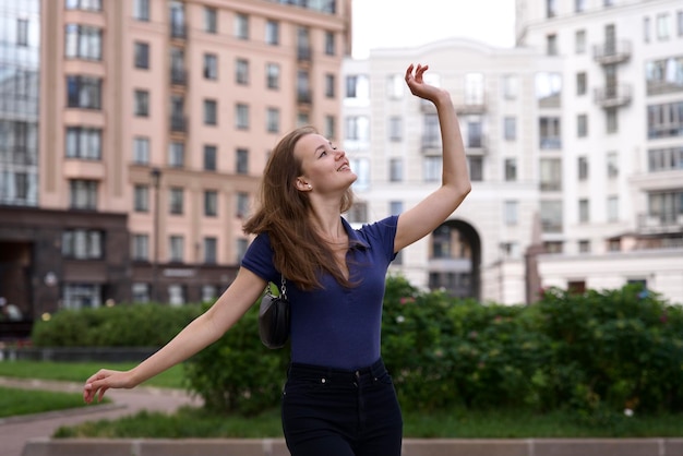 Zdjęcie szczęśliwa młoda kobieta na dziedzińcu kompleksu mieszkaniowego w mieście