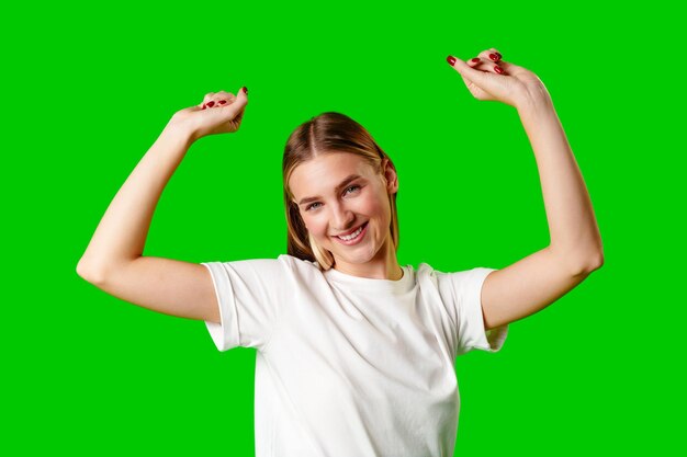 Zdjęcie szczęśliwa młoda kobieta podnosząca pięści na zielonym tle