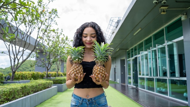 Szczęśliwa młoda kobieta pokazując ananasa Kobieta z owocami ananasa uśmiechnięta zdrowa i radosna Mixedrace azjatycki model rasy kaukaskiej z ananasem