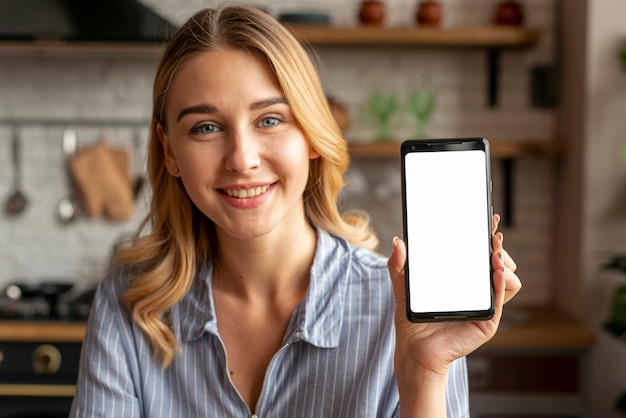 Zdjęcie szczęśliwa młoda kobieta pokazuje jej telefon