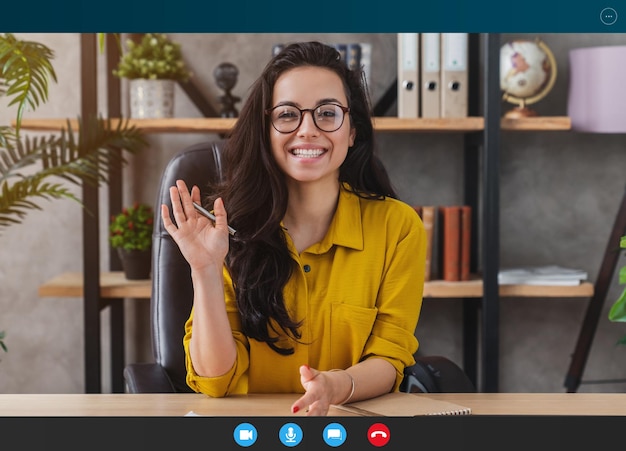 Zdjęcie szczęśliwa młoda kobieta rozmawia przez kamerę internetową lub prowadzi rozmowę w celu rozmowy wideo o pracy
