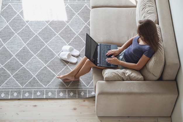 Szczęśliwa Młoda Kobieta Siedzi Na Kanapie I Korzysta Z Laptopa W Domu