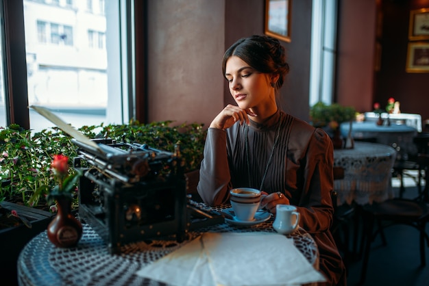 Szczęśliwa młoda kobieta siedzi przy stole w kawiarni