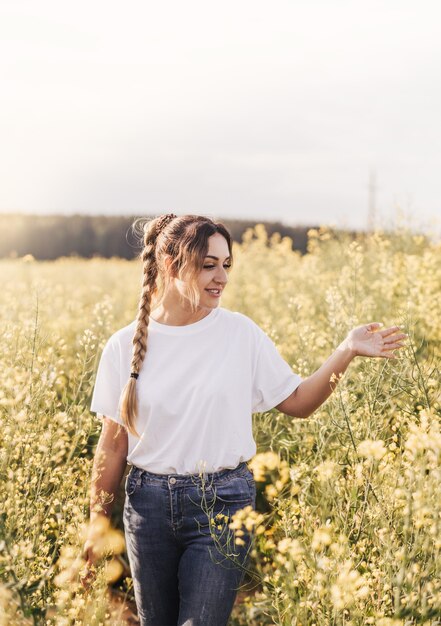 Szczęśliwa młoda kobieta spacerująca w żółtym polu w letni dzień