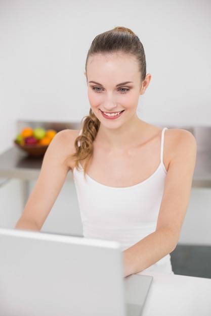 Szczęśliwa młoda kobieta używa jej laptop