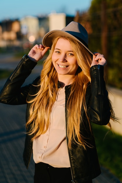 Szczęśliwa młoda kobieta w kapeluszu spaceru w mieście latem