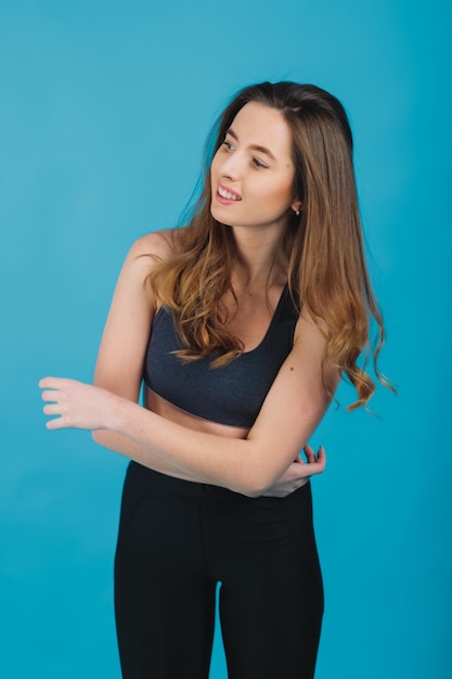 Szczęśliwa młoda kobieta w sportowej odzieży uśmiechnięta Muskularny model fitness na niebieskim tle