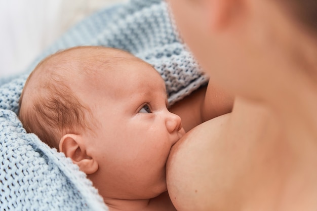 Szczęśliwa młoda mama karmienia piersią i tulenie dziecka.