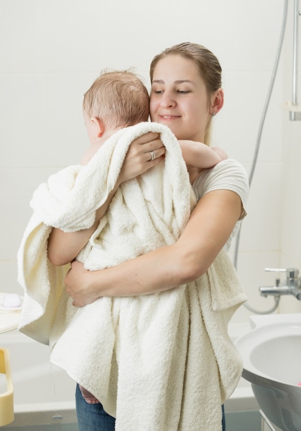 Szczęśliwa młoda matka trzymająca dziecko po kąpieli
