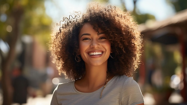 Szczęśliwa młoda mieszana kobieta z fryzurą afro uśmiechającą się w słonecznej pogodzie miasta